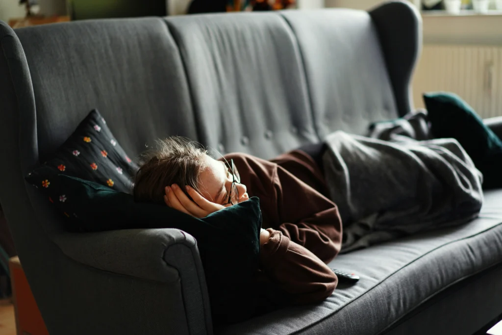 Person sitting on a couch reflecting, taking a break to manage low motivation and mental fatigue.