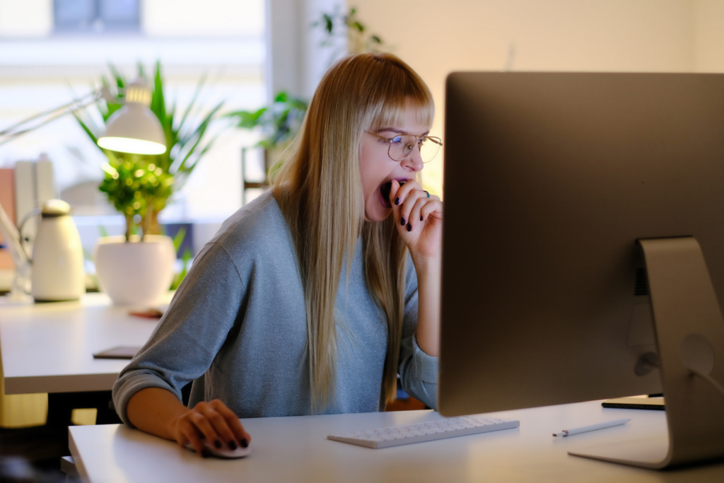 Woman at a desk late in the evening with a to-do list, looking tired but still working