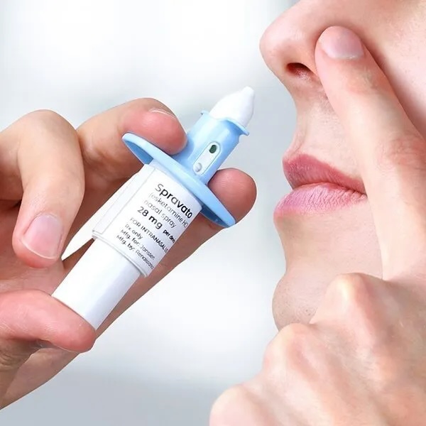Person holding a SPRAVATO nasal spray device near the nose