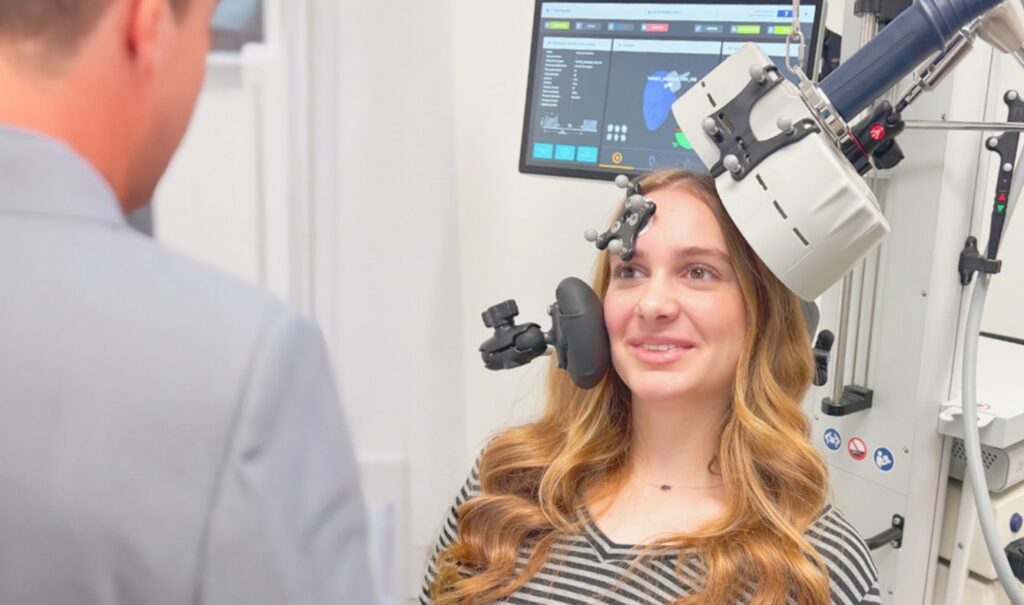 Patient receiving transcranial magnetic stimulation with a TMS coil positioned at her head